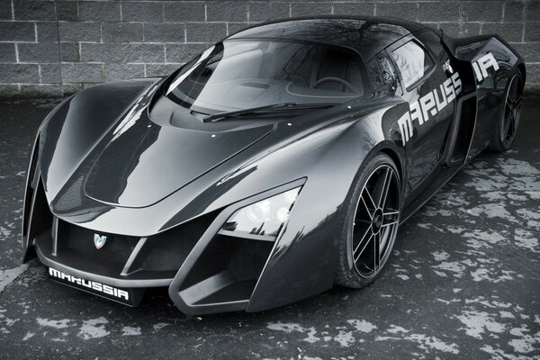 Photo of a marusia sports car in gray against a brick wall