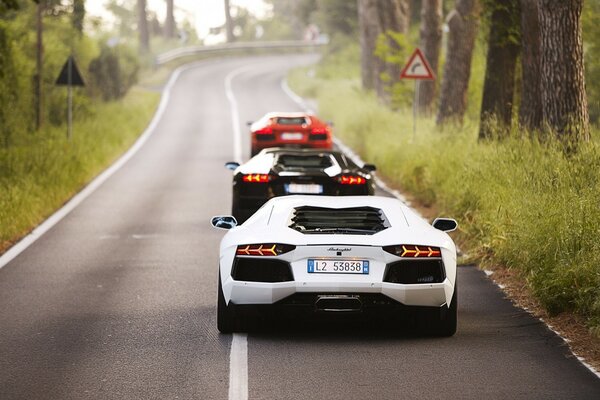 Tres coches en una fila van por la carretera