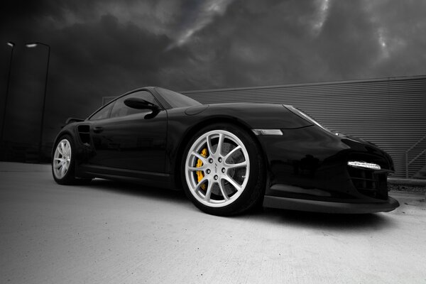 Black racing car with beautiful wheels on the background of a storm