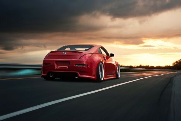 Voiture rouge sur la route sur fond de coucher de soleil