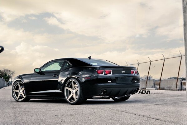 A black car outside the gate. Asphalt