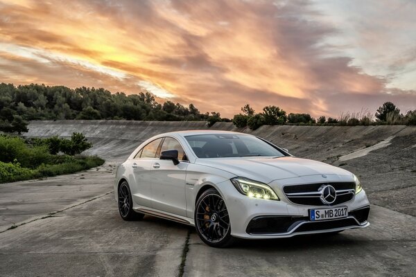 Voiture avec des phares lumineux sur fond de coucher de soleil