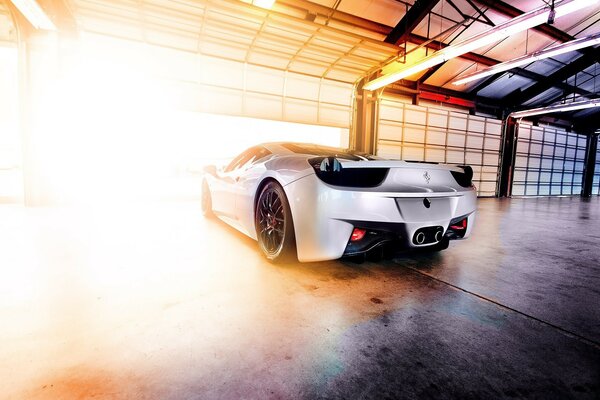 White Ferrari on the way out of the garage in the light of the sun