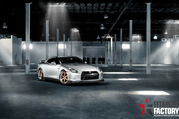 A grey sports car in an empty hangar