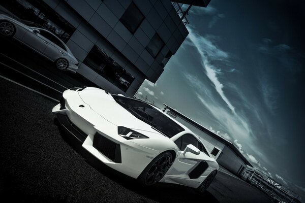 A white car is driving fast on the road