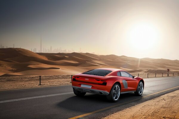 A red car is driving on a desert road