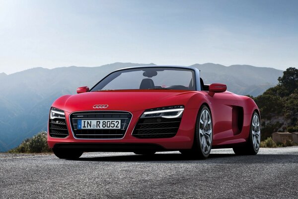 Scarlet AUDI car in front of a mountain peak