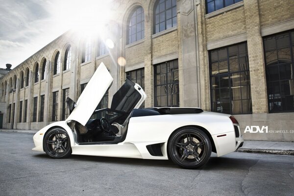 A modern car on the background of a building in the rays of the sun