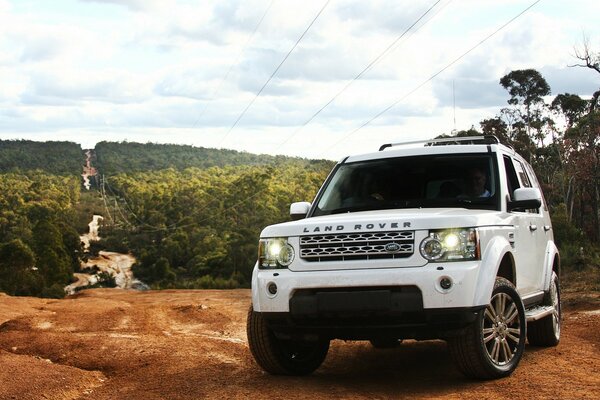 A white Land Rover on the road. Landscape with forest