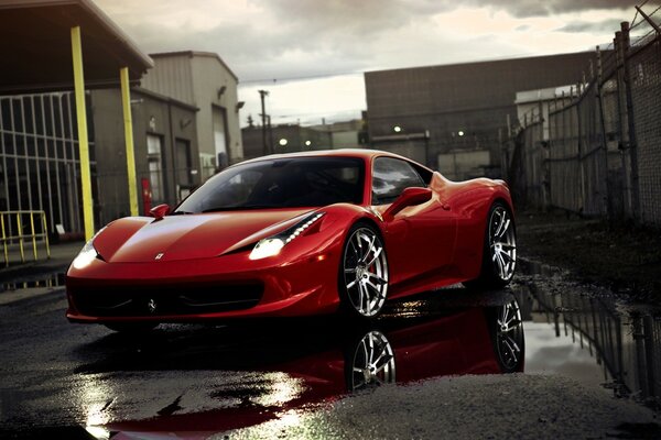 A red car rushes along the sidewalk