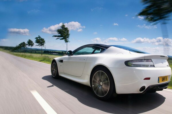 Un coche blanco viaja por la carretera en medio de un Pali y un cielo azul