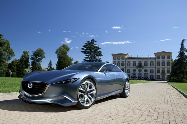 Mazda with chrome wheels on paving stones on the background of the mansion