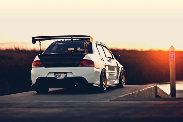 Une voiture de course part au coucher du soleil