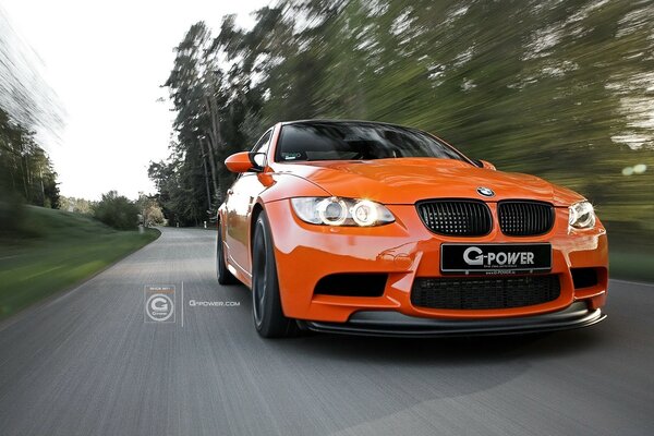 An orange car rushes along an asphalt road