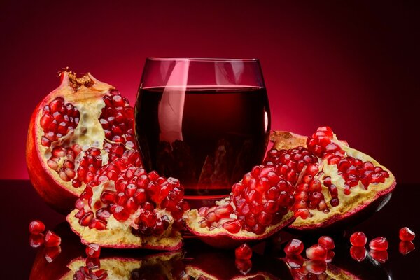 Pomegranate with a glass on a red background