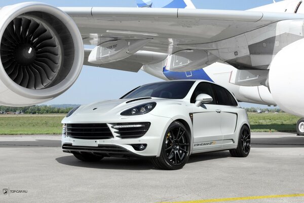 A white car under the wing of an airplane