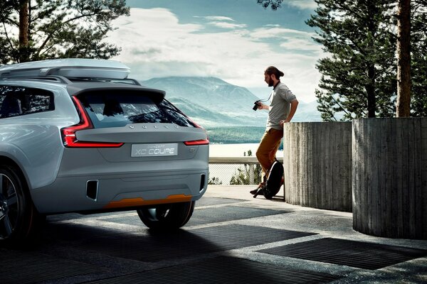 A man stands next to a car against the background of nature