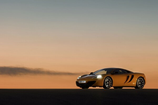 Yellow car on the background of orange-blue sky