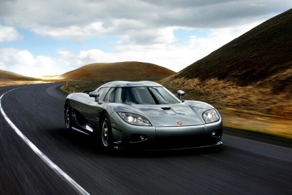 A sports car is racing along a hilly road