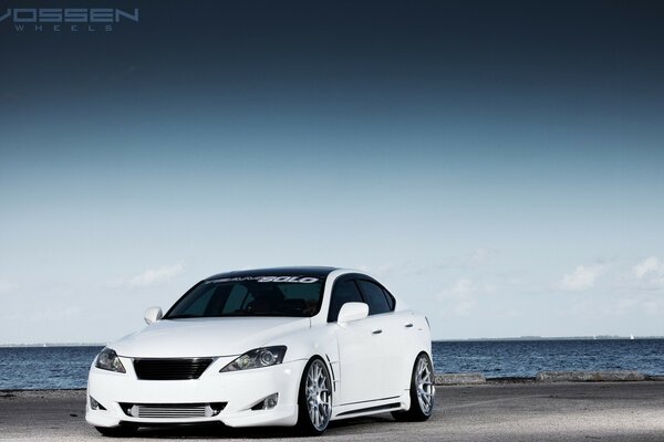 Coche blanco Lexus en la orilla del mar