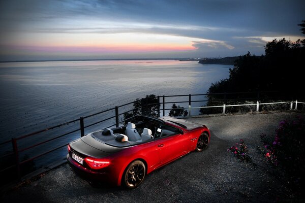 Voiture à toit ouvert de couleur rouge sur la vue de la mer