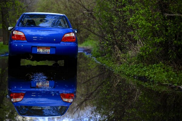 Coche azul en carretera mojada