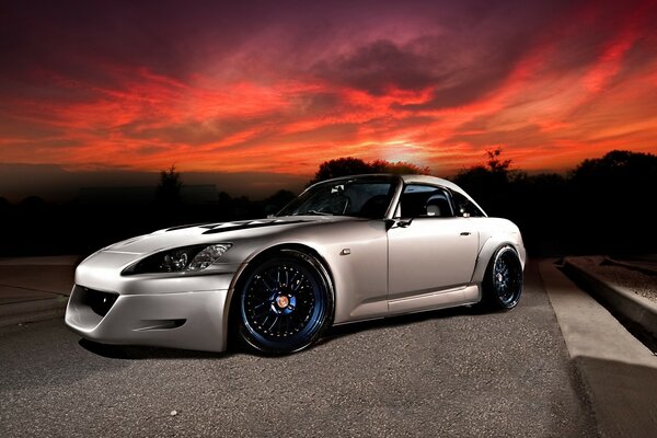 Silver sports car on the background of a fiery sky