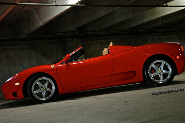 A red convertible on the background of a gloomy parking lot