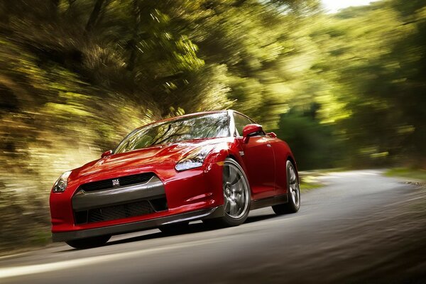 A red sports car rushes along the asphalt in the middle of the forest