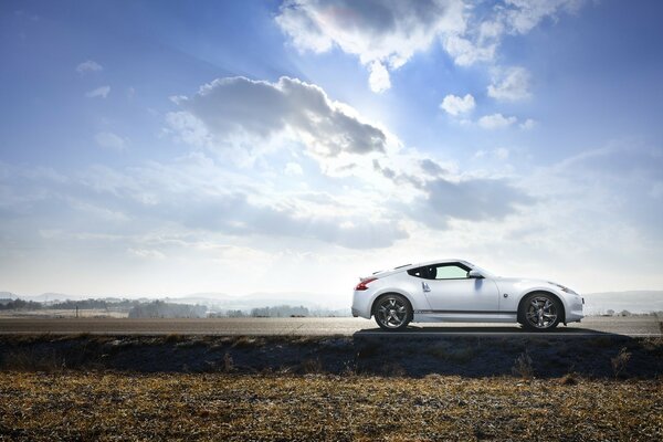 A white car stands against a blue sky