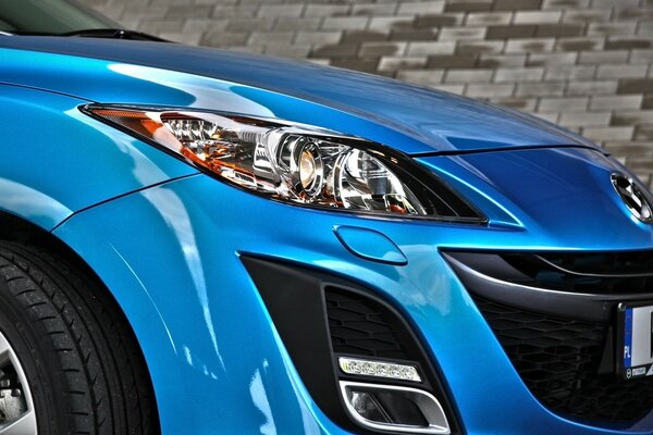 The headlight of a blue car in close-up