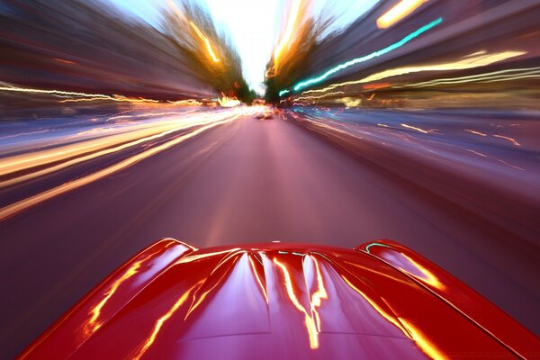 एक लाल स्पोर्ट्स कार फोटो में धुंधले ट्रैक के साथ दौड़ती है