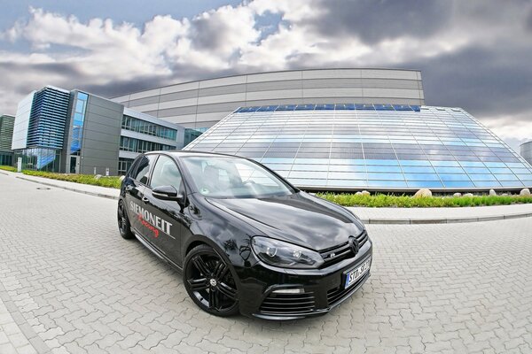 A black VW Golf R stands in front of the building