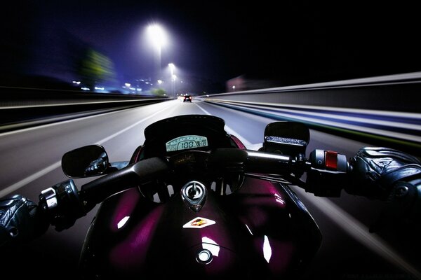 Vista de la pista iluminada desde detrás del manillar de la motocicleta