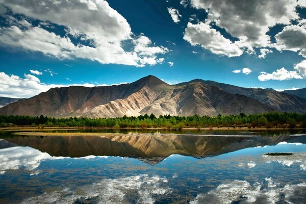 White running clouds over the mountains and the water surface