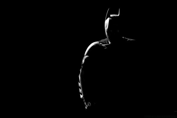 Batman is illuminated at night black background