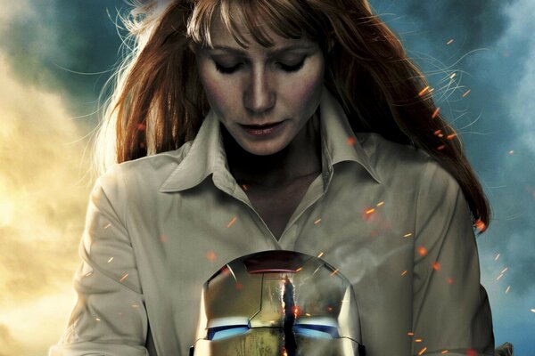 A red-haired woman with an iron man mask in her hands. Sparks