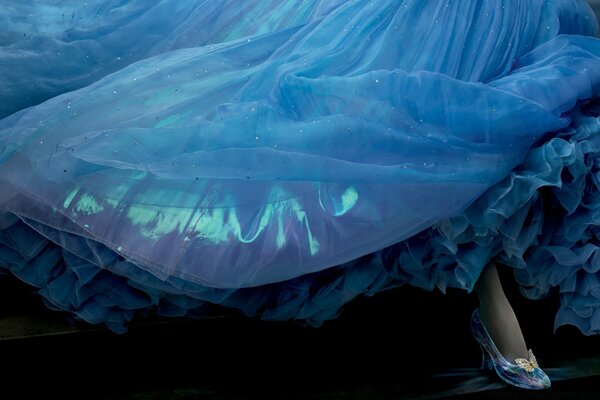 Blue airy dress. A woman s foot in a shoe from under the hem of a dress