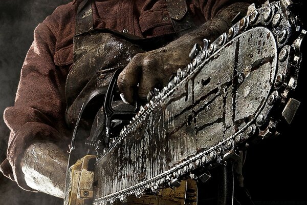 An old chainsaw in the hands of a man in a shirt