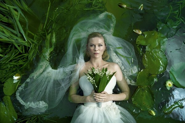 Novia con un ramo de lirios del valle en un vestido blanco