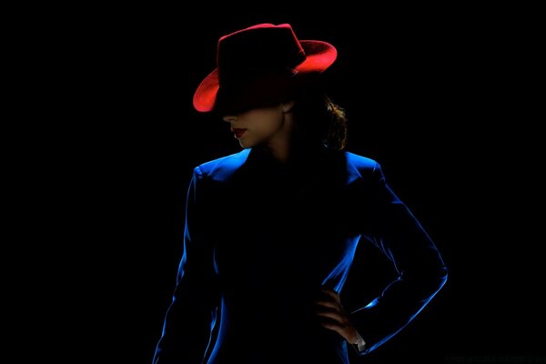 Ragazza snella in abito blu e con cappello rosso