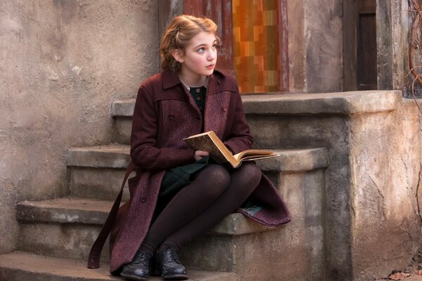 Fille avec une coiffure rétro en manteau sur les Marches de l escalier