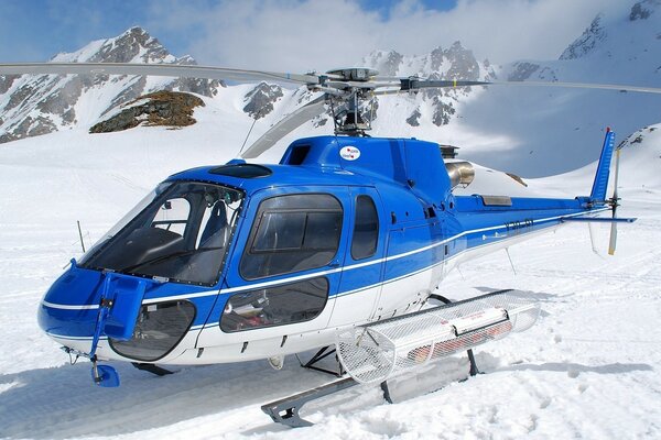 A blue helicopter stands on a snowy peak