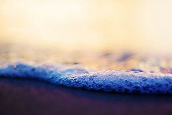 Vagues de mousse sur le sable de la plage