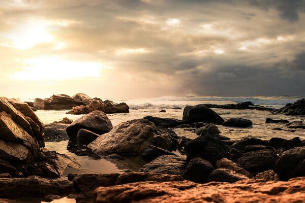 Large stones on the shore against a cloudy sky