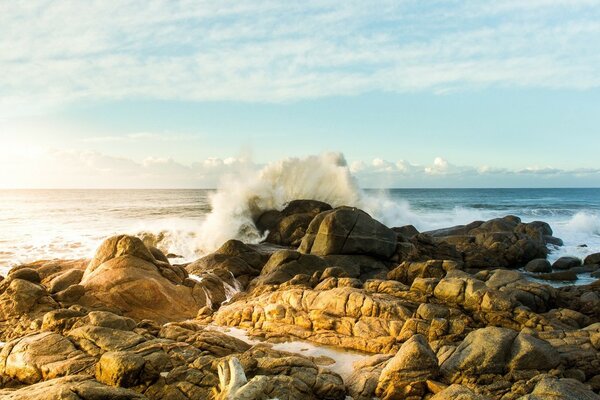 Une vague se brisant sur de grosses pierres sur le rivage