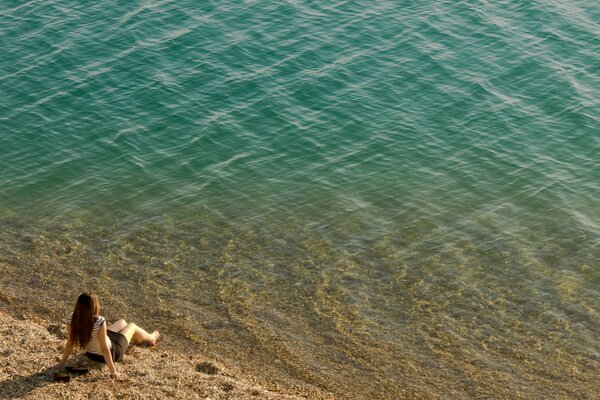 La costa y la chica sentada en la orilla