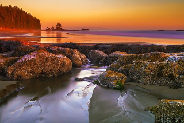 El agua que fluye a través de las rocas en el fondo de la puesta de sol