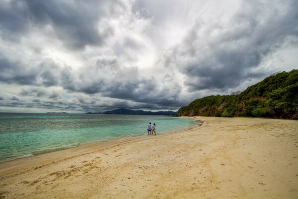 Dos hombres caminando por una playa salvaje