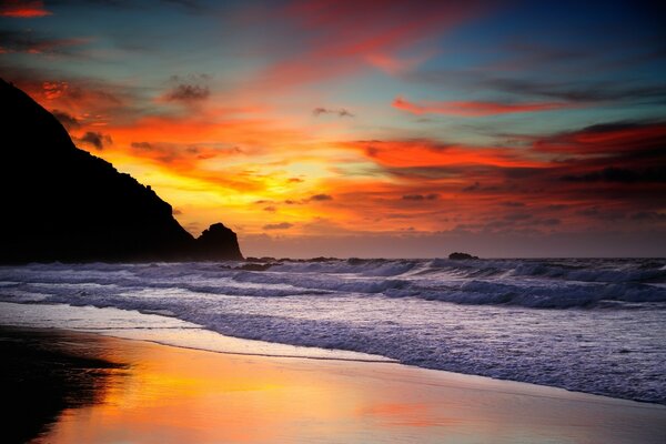 A picture of the ocean tide on the background of sunset